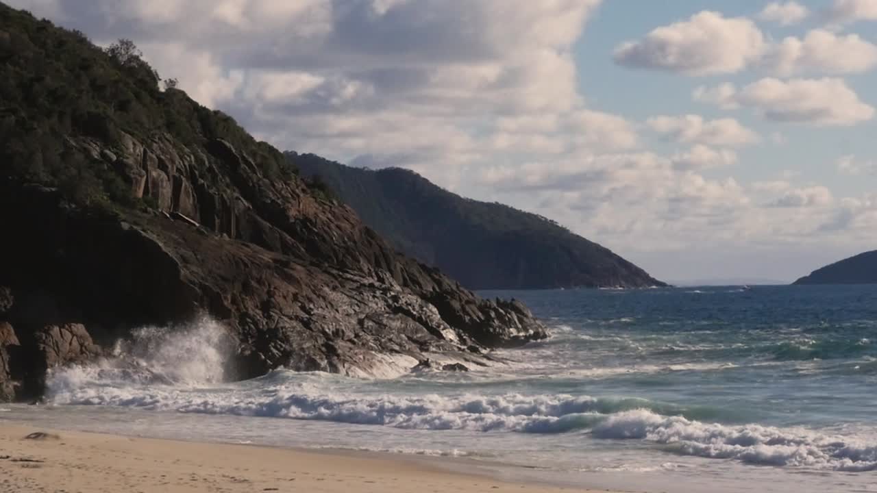 Ripresa al rallentatore di onde oceaniche che si infrangono contro le rocce sulla spiaggia a Newcastle Port Stephens, NSW, Australia 1920x1080 HD.