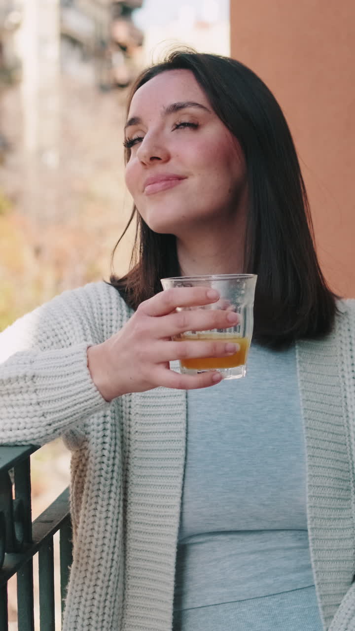 Mulher aproveitando suco de laranja na varanda