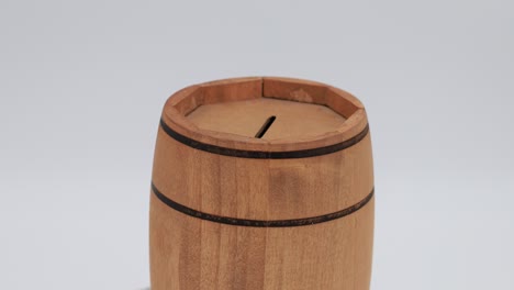 wooden barrel-shaped money box rotates clockwise