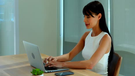female executive using laptop and mobile phone