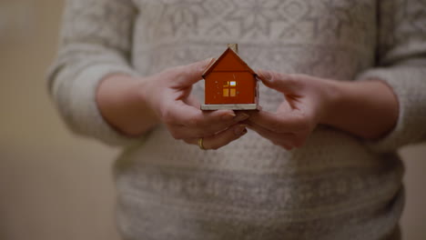 woman holding small metal house symbolizing homeownership