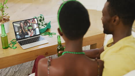 pareja afroamericana en una llamada de video portátil celebrando el día de san patricio con amigos