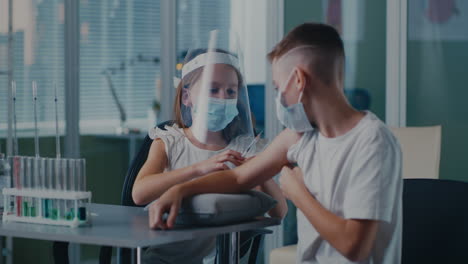 children in face masks and shield during a medical injection