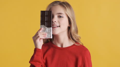 teenage caucasian girl holding chocolate bar in front of the camera.