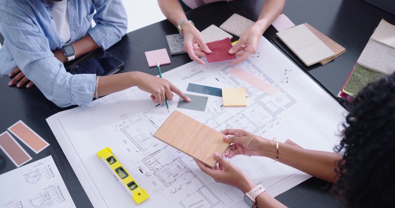 Diverse female designers placing wood sample, arranging swatches on plan in office, checking scale