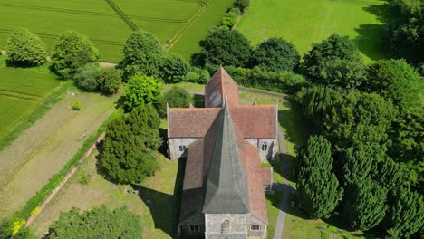 A-slow-push-in-above-St-John-the-Evangelist-church-in-Ickham,-Kent,-surrounded-by-greenery