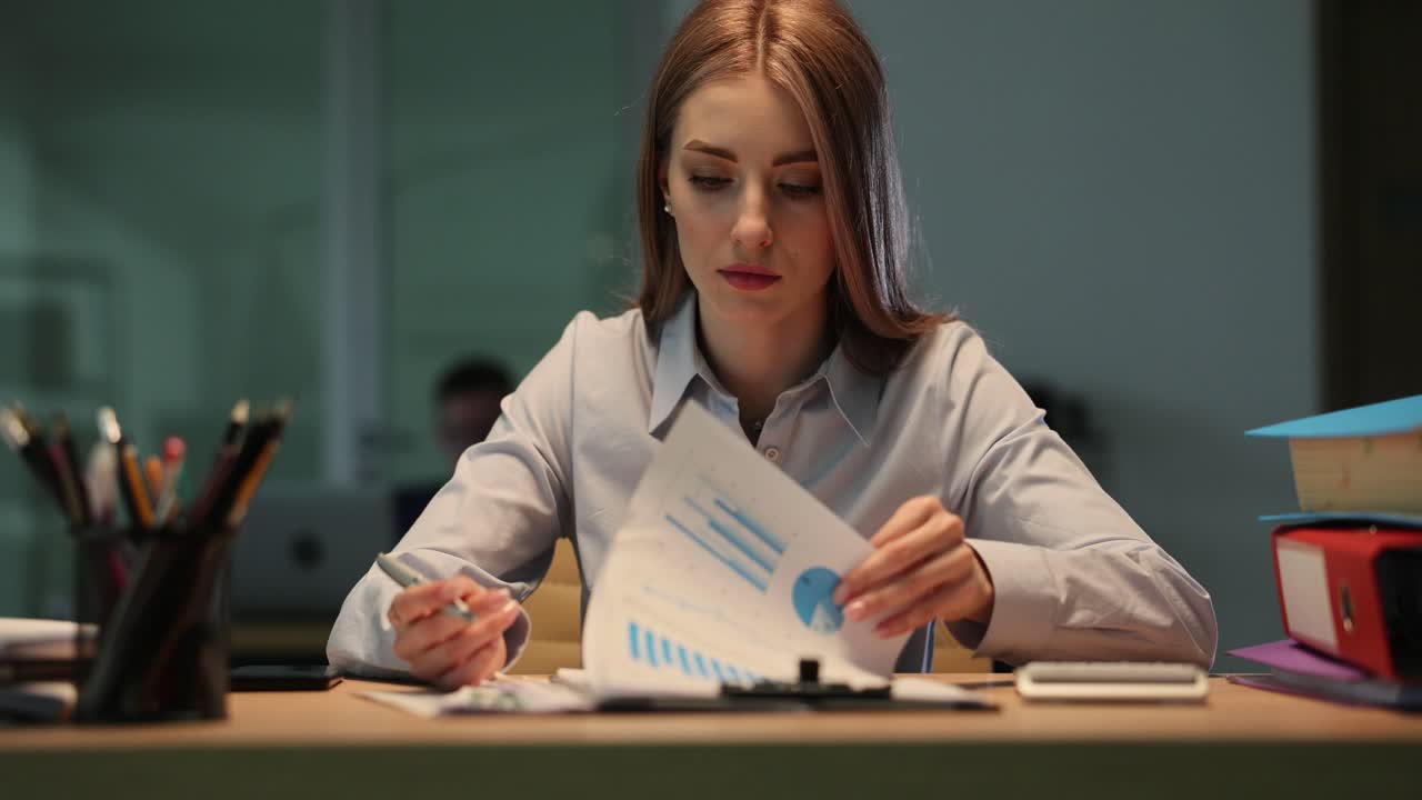 Professional Woman Analyzing Documents and Reports in an Office