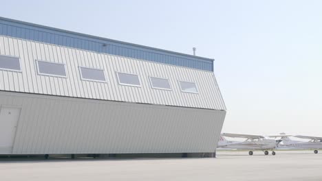 airfield hangar doors opening revealing parked twin engine airplane