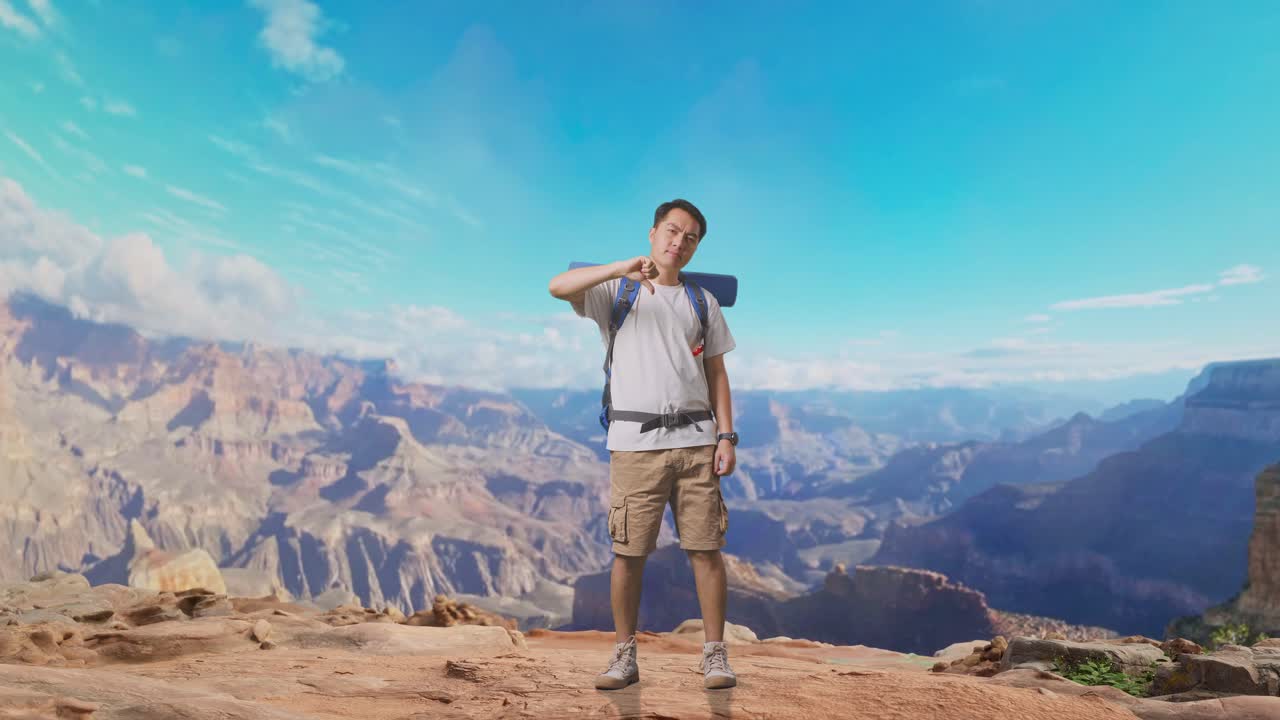 Full Body Of Asian Male Hiker With Mountaineering Backpack Showing Thumbs Down Gesture While Traveling At The Top Of Mountain
