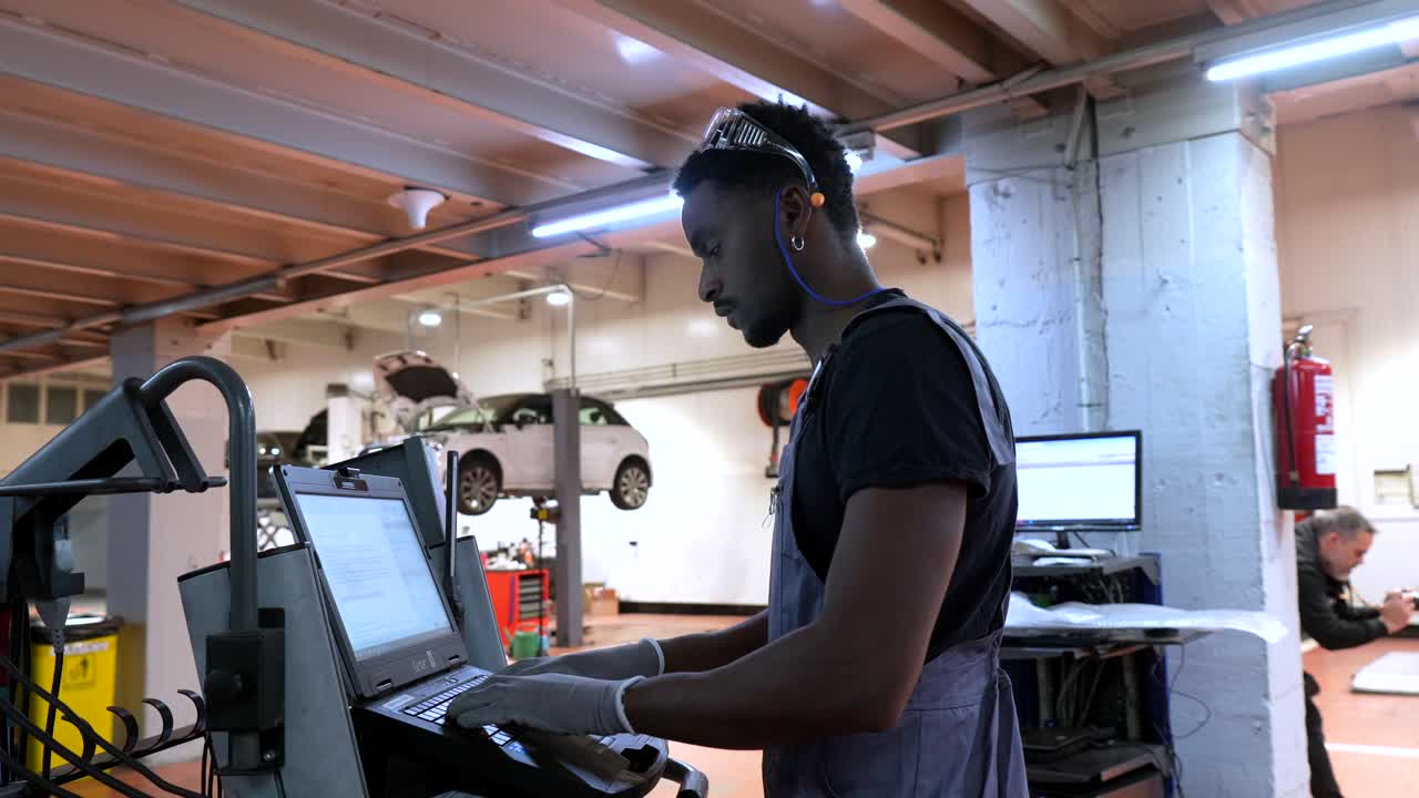 Mechanic using laptop for car diagnostics in auto repair shop