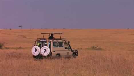 a man sits in a parked vehicle on the plains looking around