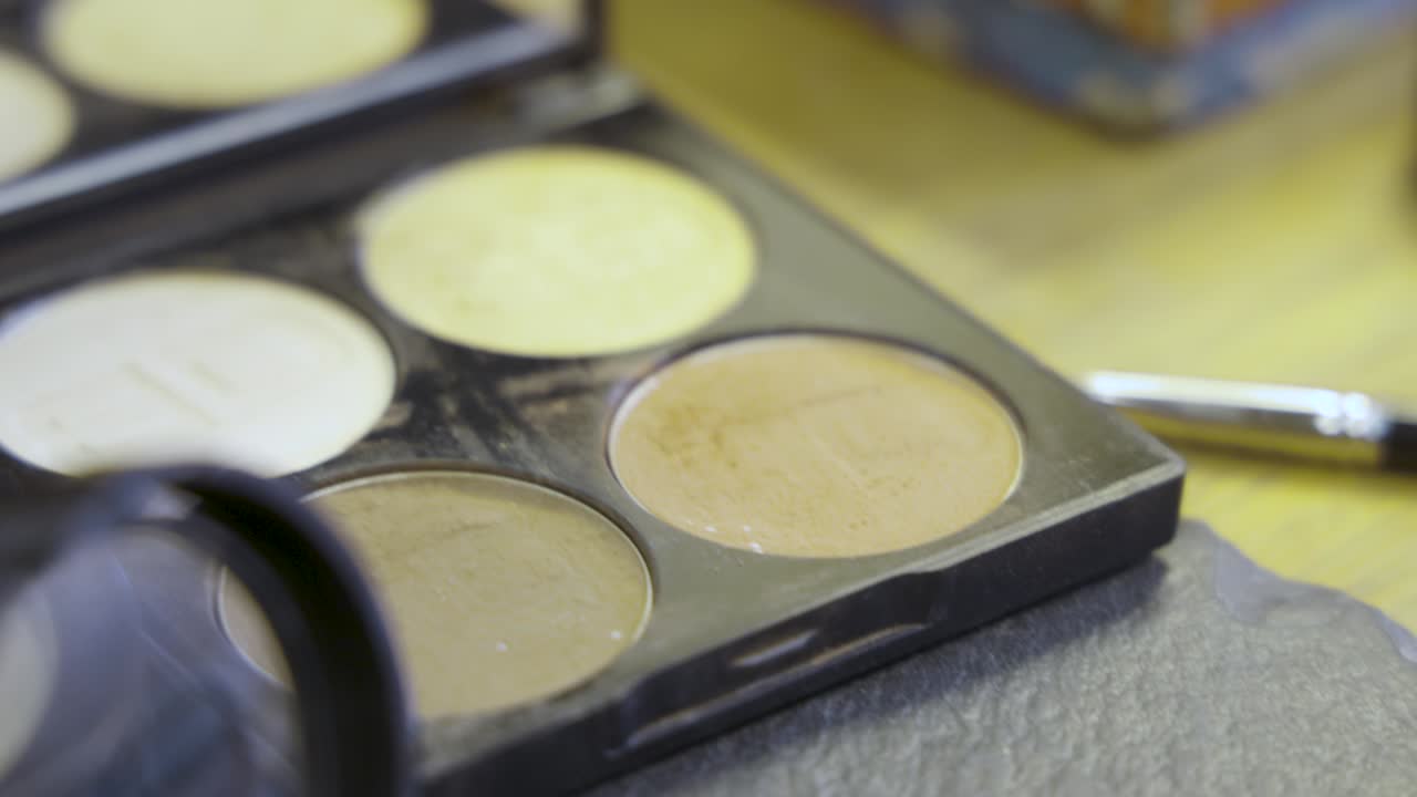 cepillo de maquillaje sumergiéndose en una paleta cosmética en el salón de belleza