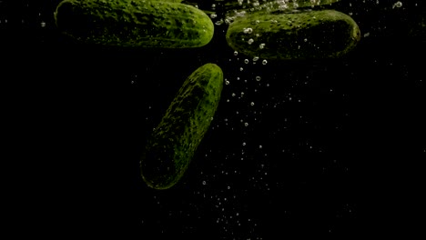 cucumbers  falling into water on black background. bright high quality video