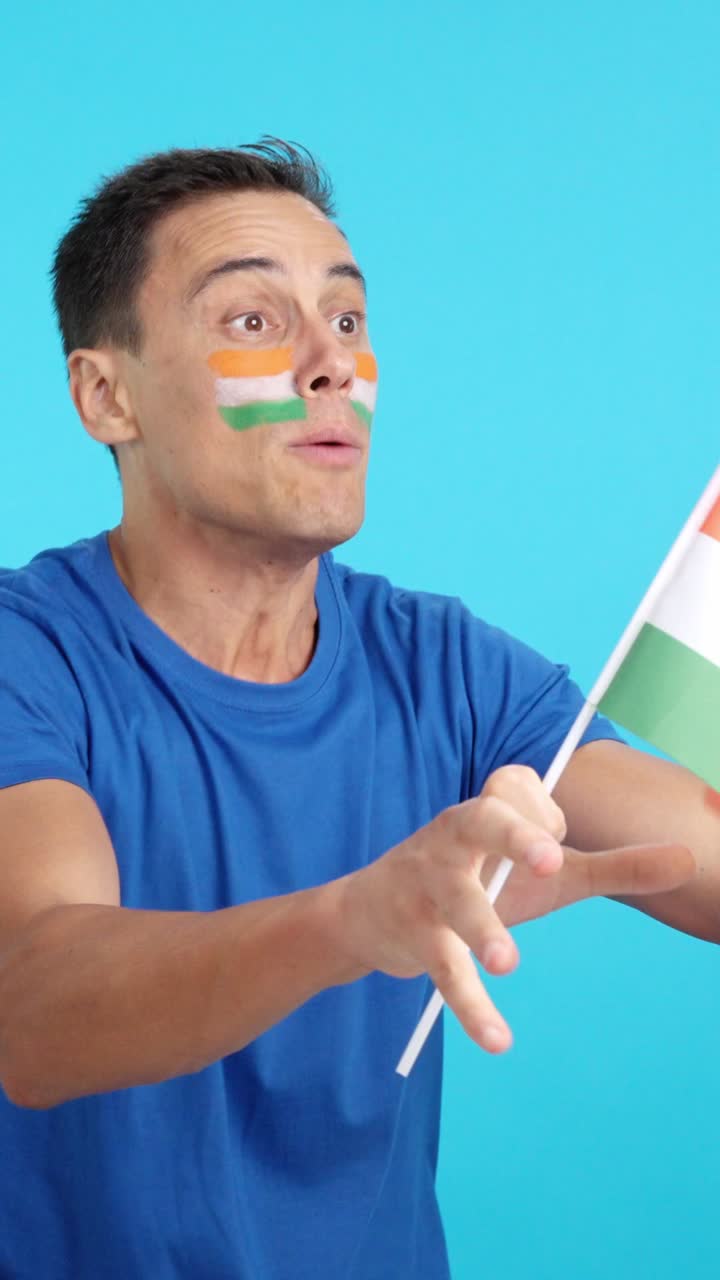 Indian supporter screaming and waving a national flag looking away