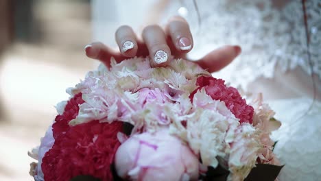 bride-is-stroking-the-wedding-bouquet-as-if-exploring-it-considering-fingering-close-up-slow-motion
