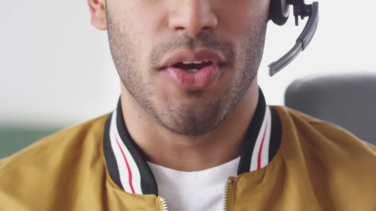 hombre de raza mixta usando auriculares con micrófono en la oficina creativa