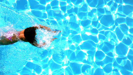 Woman-in-pink-bikini-swimming-across-the-pool