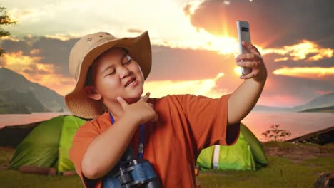 happy child taking selfie at sunset camp