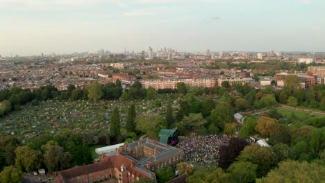 Kreisende-Luftaufnahme-Eines-Konzerts-Mit-Der-Skyline-Von-London-Im-Hintergrund