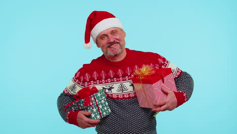 Cheerful-man-in-Santa-sweater-presenting-two-Christmas-gift-boxes,-stretches-out-his-hands-to-camera