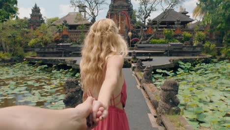 Reisepaar-Händchen-Haltend,-Glückliche-Frau-Lächelnd,-Führender-Freund,-Der-Den-Saraswati-Tempel-Erkundet-Und-Spaß-Beim-Sightseeing-Hat-Kultur-Von-Bali-Indonesien