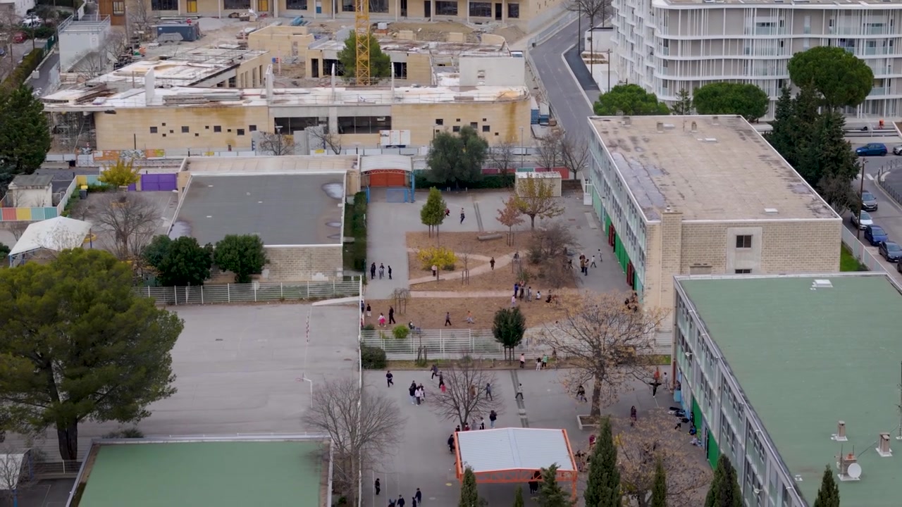 Cortile scolastico ed edifici accanto a gru edili a Montpellier, Francia, vista aerea