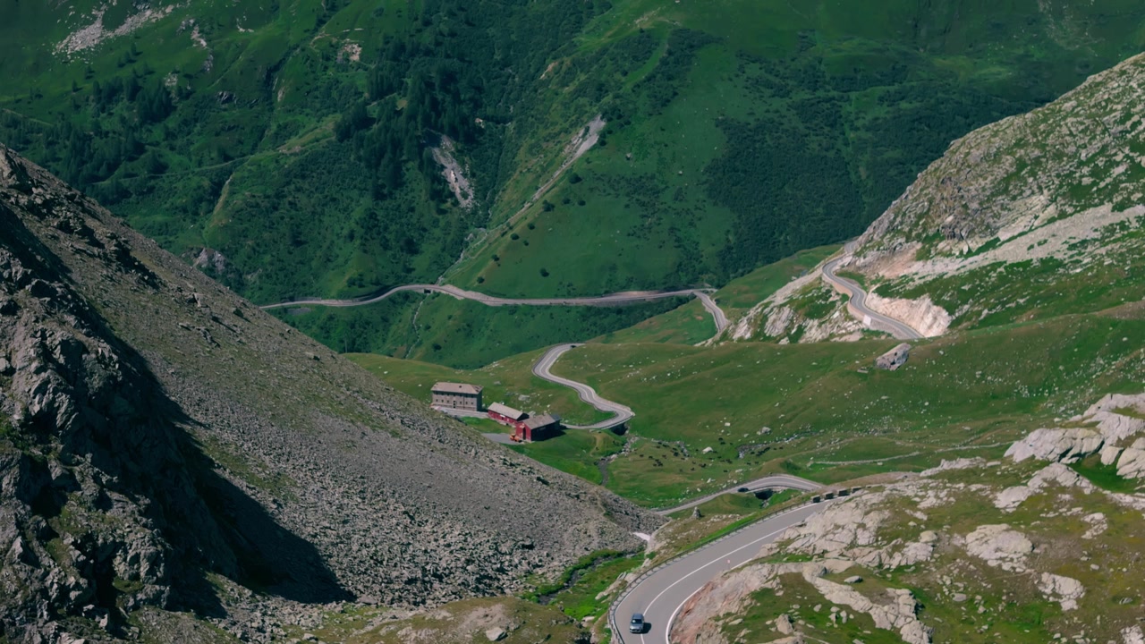 Strada di montagna tortuosa ed edifici al Passo del Gran San Bernardo nelle Alpi Svizzere, paesaggio estivo