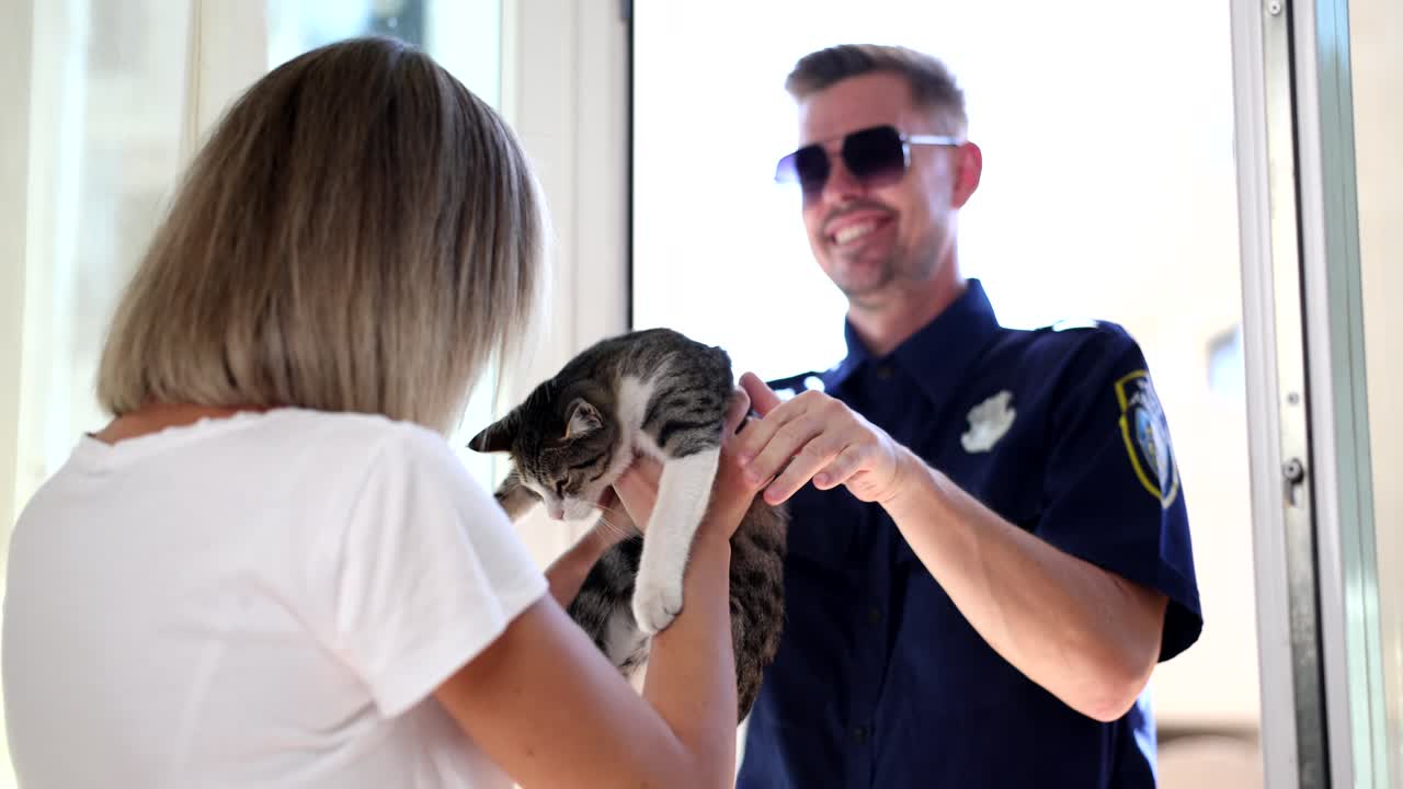 Woman holding a cat receiving a police officer at the door