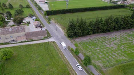 aerial tracking shot of a white delivery truck driving through the countryside