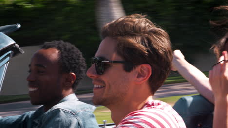 Young-adult-friends-on-the-road-in-a-convertible,-close-up