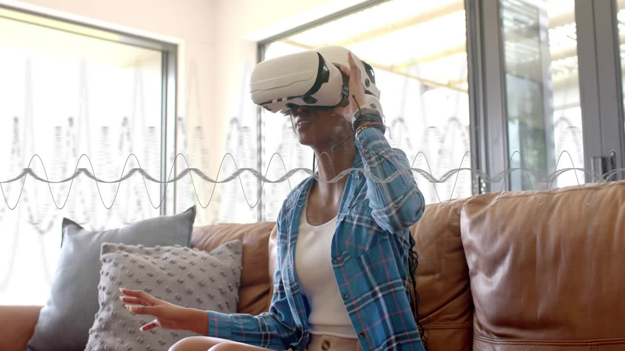 Woman sitting on couch using white VR headset, adjusting unit, exploring floating technology UI
