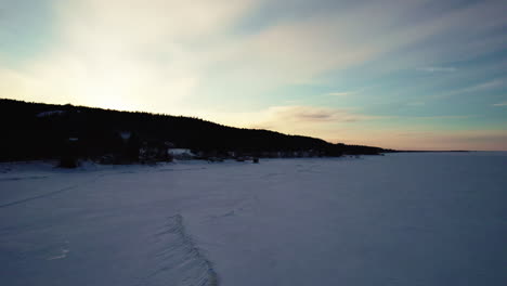 Flying-drone-above-a-frozen-lake-in-canada-at-golden-hour