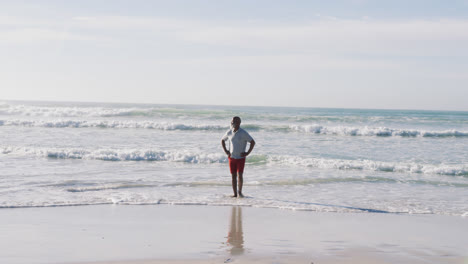 un anciano afroamericano caminando y sonriendo en la playa