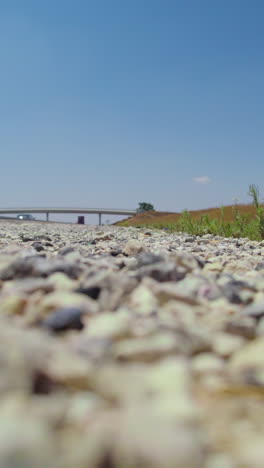 low angle view of cars driving on the highway, ground level, clear sky, a man beyond a farmer's shout in the background - vertical video