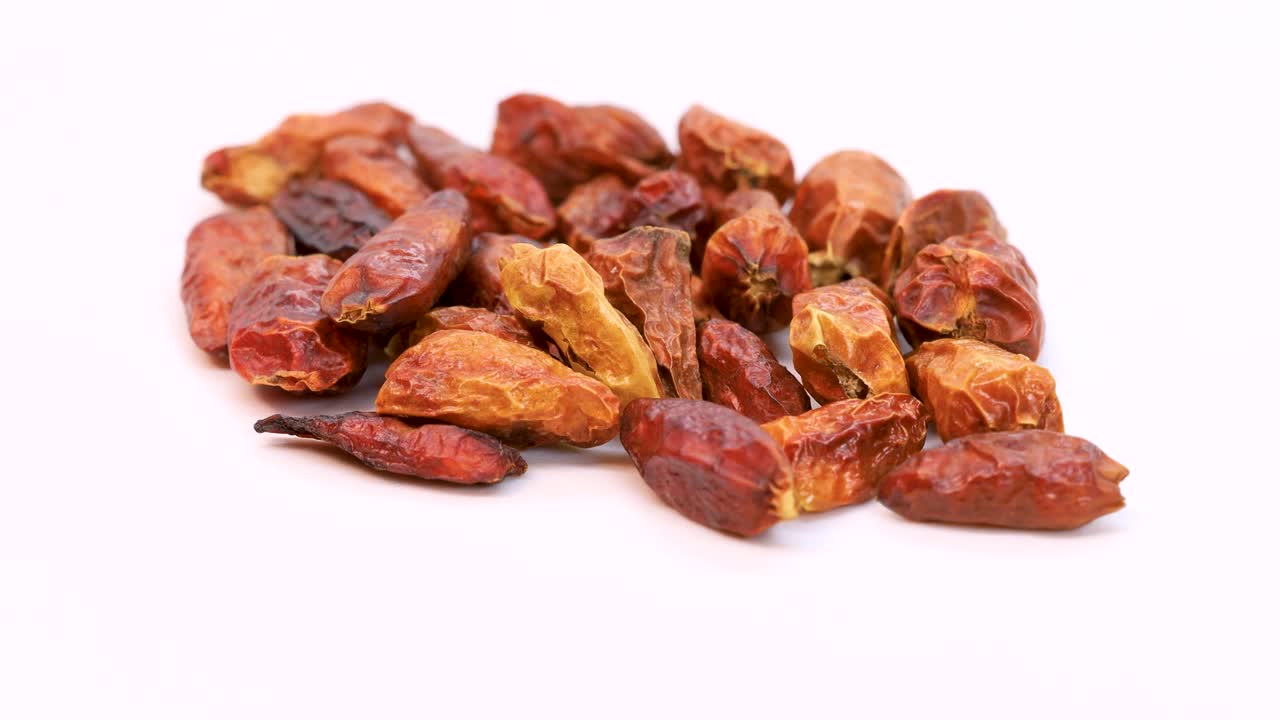 Macro shot of dried cayenne peppers rotating on white surface, close up view in 4k