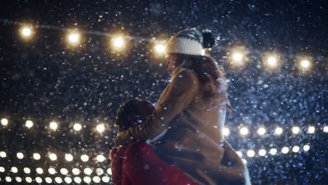 romántica noche nevada de invierno: pareja de patinaje sobre hielo se reúnen en la pista de hielo y se divierten. pareja de skating boyfrined levanta a su hermosa novia y gira. amor, baile, patinaje artístico. movimiento lento medio