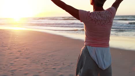 senior woman standing with arms outstretched on beach