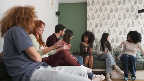 happy multiethnic friends sitting on couch talking at home