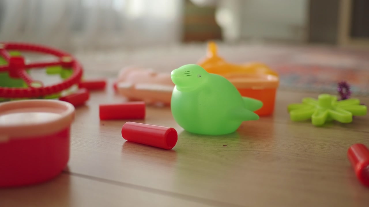 Green Bird Toy and Other Colorful Toys on Wooden Floor