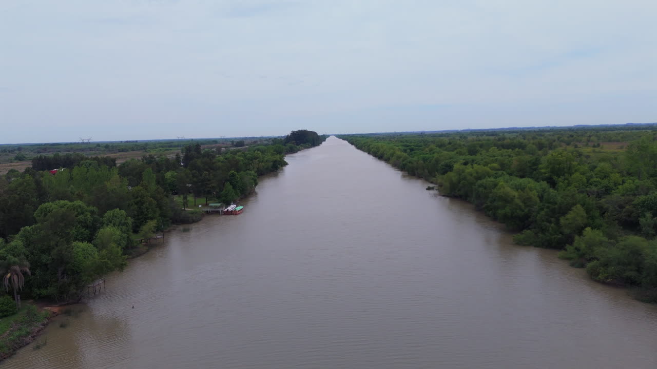 Wide river cutting through dense forest viewed from above in Paraná Delta, Argentina.