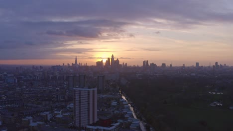 circling aerial drone shot of london canal towards city skyline at sunset