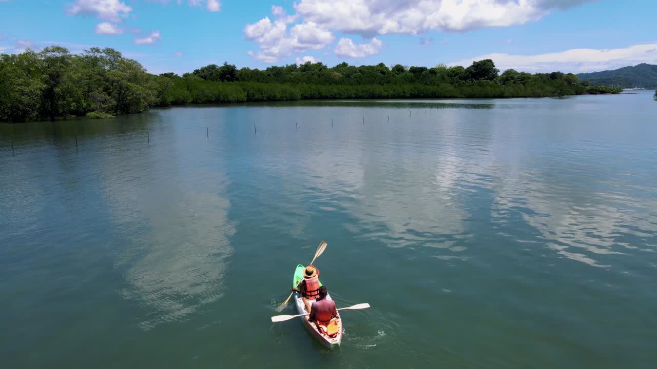 una pareja en un kayak en el océano de phuket, tailandia, hombres y mujeres en un kayak en una isla tropical con palmeras y bosque de manglares.