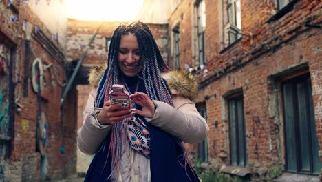 young woman using a phone in an urban alleyway