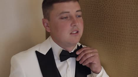 a groom getting ready in a white tuxedo