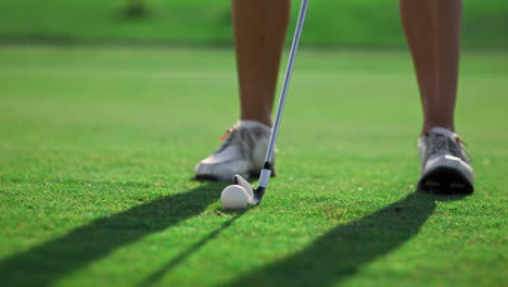 golf player legs stand at golf course grass. woman swinging golfing shot outside