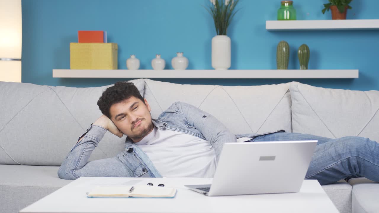 소파에 누워 있는 남자가 휴식을 취하고 있습니다.