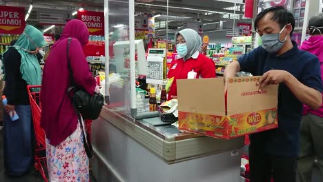 people with face mask buying groceries in the supermarket cashier during virus pandemic.