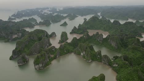 aerial - halong bay's limestone islands and emerald waters, surrounded by misty atmosphere. vietnam