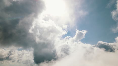 Thin-white-clouds-move-gently-with-the-wind-while-in-the-background-large-thick-gray-clouds-slowly-slide-in-front-of-the-sun-and-blue-sky