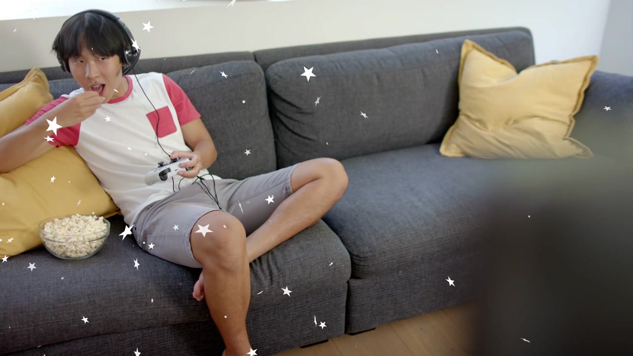Uomo che inizia una partita, impugnando il controller, facendo uno spuntino tra una giocata e l'altra, con una sovrapposizione di stelle che brillano sopra il divano.